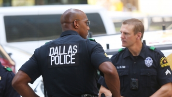 Dallas police patrol a prayer vigil after deadly shooting spree kills five officers.