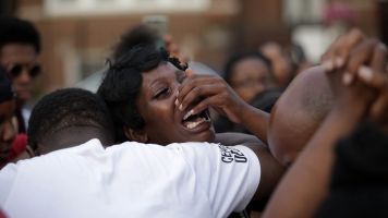 A woman grieves as she attends a vigil for Africa Bass, who was killed as she walked through her apartment complex July 27,