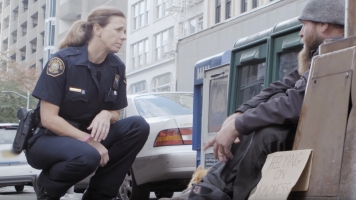 A Portland police officer speaks with a person who is homeless