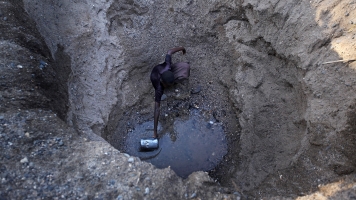 Children from the remote Turkana tribe in Northern Kenya dig a hole in a river bed to retrieve water.