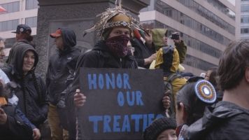 Anti-pipeline activist holds up a sign reading "honor our treaties"