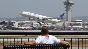A United Airlines jet takes off near an air traffic control tower at LAX.