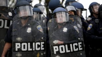 Baltimore Police officers in riot gear look toward protestors.