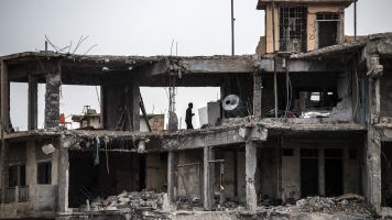A man stands in the ruins of a building destroyed during fighting between Iraqi forces and ISIS.