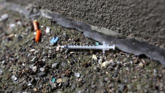 A needle used to inject heroin sits in a street outside a clinic