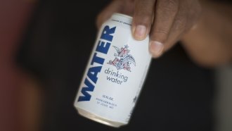 A resident holds a can of water donated by the Anheuser-Busch company.