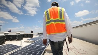 A worker installs solar panels on a rooftop in San Antonio, Texas