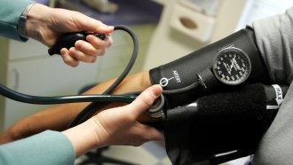 Doctor reads a blood pressure gauge.