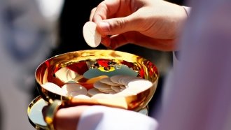 Priest holds a Holy Communion wafer.