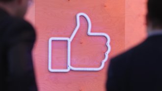 People walk past a Facebook logo