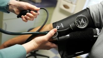 A doctor reads a blood pressure gauge.