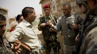 An interpreter speaks with Kurdish villagers during a humanitarian mission involving US, Iraqi and Kurdish forces.