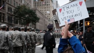 A girl holds up a sign thanking veterans at the nation's largest Veterans Day Parade in New York City.