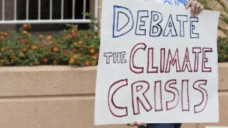 A protester holds a sign urging climate debate