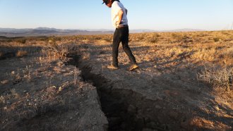 A man inspects a fissure caused by an earthquake