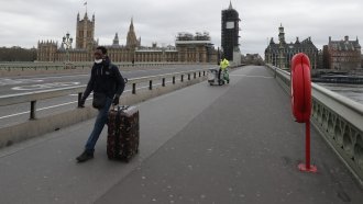 A man wheels his suitcase across Westminster Bridge.