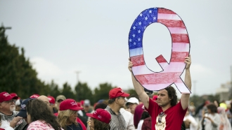 David Reinert holding a Q sign waits in line with others to enter a campaign rally with President Donald Trump in Wilkes-Barr