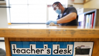 Custodian Joel Cruz cleans a teacher's desk.