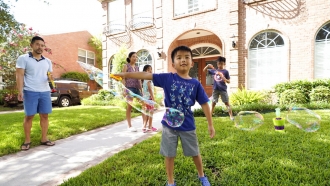 Caption Jesse Yip, 5, makes a bubble as he plays with family at their home.