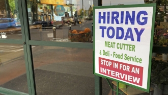 A sign that reads "hiring today" is shown at a grocery store.
