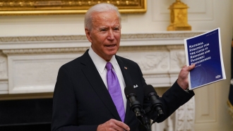 President Joe Biden holds a booklet as he speaks about the coronavirus