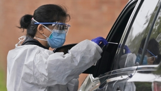 A member of a COVID-19 testing team prepares to administer a COVID-19 swab at a drive-thru testing site in Lawrence, N.Y.