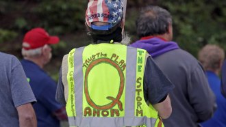 A person wears a vest supporting QAnon at a rally in Olympia, Wash