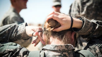 Woman in Army uniform ties back hair