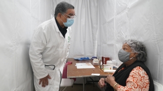 New York: Dr. Victor Peralta talks with a patient before giving her the second dose of the COVID-19 vaccine.