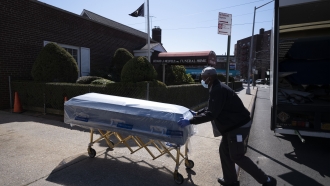 Person pushes casket on gurney
