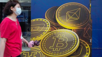 A woman walks past an advertisement for Bitcoin in Hong Kong