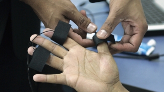 A polygraph examiner applies electrodes on the fingers of a subject.
