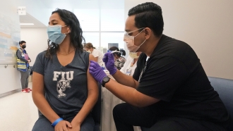 A University of Florida Pharmacy student gives a junior at Florida International University the Pfizer COVID-19 vaccine
