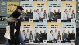 People walk past posters encouraging participation in the 2020 Census