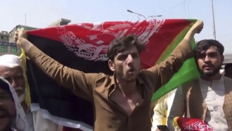 A man holds the flag of Afghanistan during a protest in Jalalabad on Wednesday, Aug. 18, 2021.