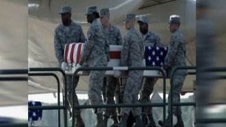 Service members carry a casket.
