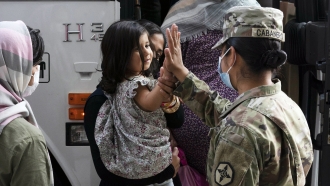 An Army Pfc. gives a high-five to a girl evacuated from Kabul, Afghanistan
