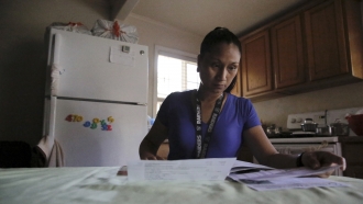 Mary Taboniar, a housekeeper at the Hilton Hawaiian Village resort in Honolulu, looks over bills at her home in Waipahu