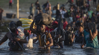 Migrants, many from Haiti, wade across the Rio Grande river from Del Rio, Texas, to return to Ciudad Acuña, Mexico