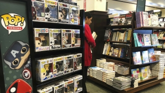 A woman stocks shelves with books at a Barnes and Noble bookstore