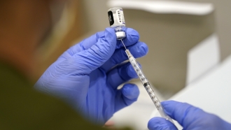 A health care worker fills a syringe with the Pfizer COVID-19 vaccine