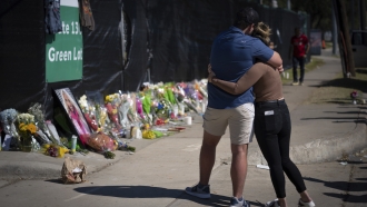 Two people hug at a makeshift memorial for Astroworld victims.