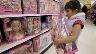 A girl looks at the doll section in a store.