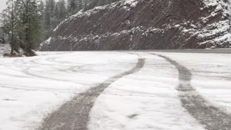 Tire marks run down a snowy road.