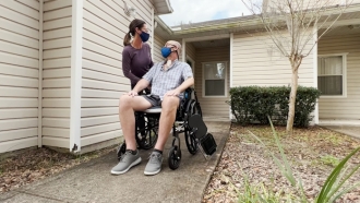 A man in a wheelchair outside his home