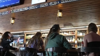 Patrons sit at a restaurant bar