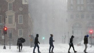 People cross a snowy Congress Street in Boston