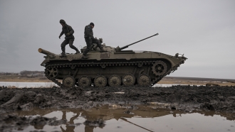 Ukrainian servicemen walk on an armored fighting vehicle