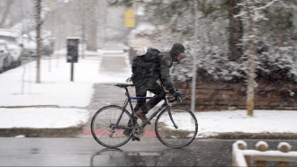 A cyclist rides as it's snowing.