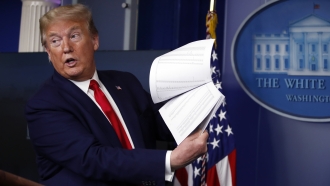 Former President Donald Trump holds up papers while speaking.